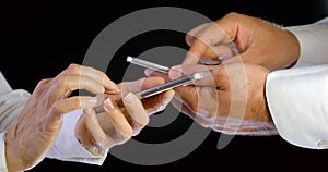 Close - up of hands of people using phone for application and wireless network concept. Black isolated background.