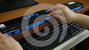 Close-up hands of person with blindness disability using computer keyboard and braille display or braille terminal a technology