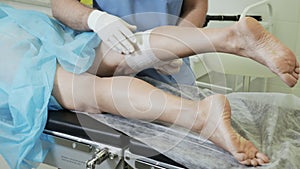 Close-up hands of phlebologist in gloves put bandage on his leg after sclerotherapy procedure