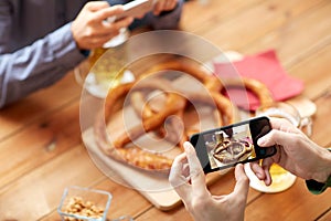 Close up of hands picturing pretzel by smartphone