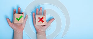 close-up of a hands placing two wooden blocks on a blue background. True and false symbols accept rejected for evaluation, Yes or