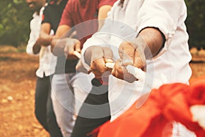 Close up of hands playing tug of war - Group of friends playing outdoor games in changing digital and technology world.