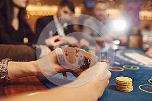 Close-up hands of a poker player checking cards in a casino.