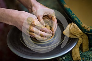 Close-up hands of potter in apron making vase from clay, selective focus. Making it together
