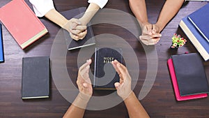 Close up hands praying on Bible at home, church in home, devotional or prayer meeting concept, Religion concept