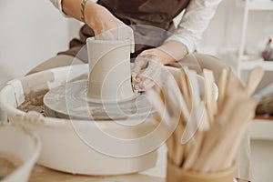 Close up of hands of professional potter molding pot shape on pottery wheel. Ceramics art concept