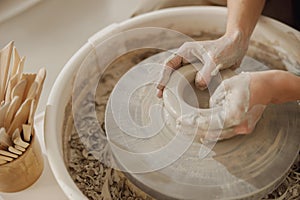 Close up of artisan's hands shaping clay bowl in pottery studio. Pottery art and creativity