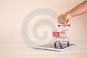 Close up hands pushing the shopping cart on smart phone or tablet at desk