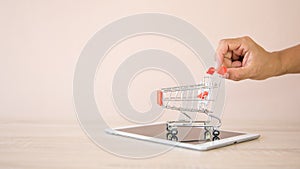 Close up hands pushing the shopping cart on smart phone or tablet at desk