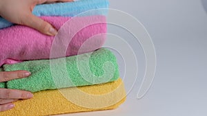 Close-up of hands putting stack of fresh bath towels on the bed sheet. Room service maid cleaning hotel room macro