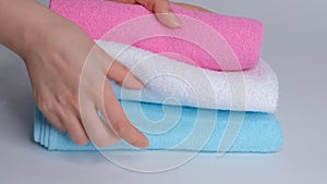 Close-up of hands putting stack of fresh bath towels on the bed sheet. Room service maid cleaning hotel room macro