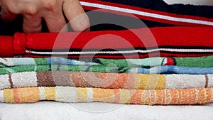 Close-up of hands putting stack of fresh bath towels on a shelf