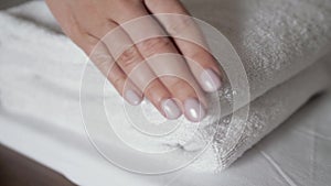 Close-up of hands putting stack of fresh white bath towels on the bed sheet. Room service maid cleaning hotel room macro