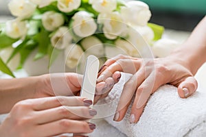 Close-up of the hands of a qualified manicurist filing the nails