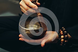 Close-up of hands with rosary playing on singing bowls. Relaxation and meditation. Alternative medicine.