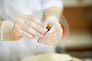 Close-up hands in rubber gloves cut off ampoule