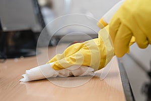 Close up of hands in rubber protective yellow gloves cleaning the white surface with a rag. Home, housekeeping concept