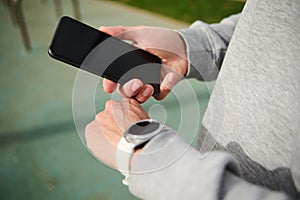 Close-up hands of a runner checking timer, clock and healthy training progress with smart wrist watch and mobile phone