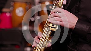 Close-up of the hands of a saxophonist on a soprano saxophone. A musician in a black shirt plays music on a wind