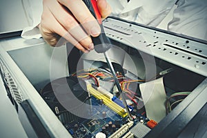 Close-up on the hands with screwdriver tool of the technician repairing a PC computer