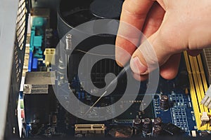 Close-up on the hands with screwdriver tool of the technician repairing a PC computer