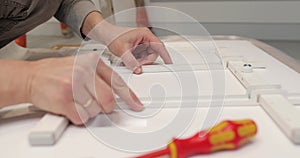 Close-up of hands and screwdrivers turning or unscrewing screws and bolts.