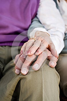 Close-up hands of senior couple resting on knee photo