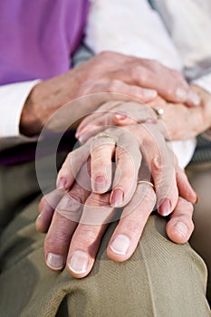 Close-up hands of senior couple resting on knee