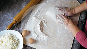 Close-up hands of senior female is kneading a dough at home kitchen, above view