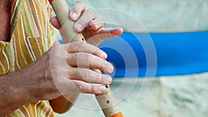 Close-up hands of senior man playing bamboo flute
