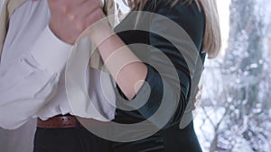 Close-up hands of senior man and young woman holding each other. Couple with age difference waltzing indoors. Camera