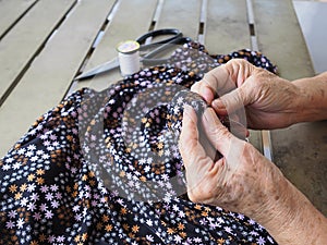 Close-up of hands senior woman`s trying to thread a needle for sewing cloth. Space for text. Concept of aged people and relaxatio photo