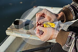 Close up of hands setting worm as bait on fishing hook. Man is holding fishing rod and line with sinkers. He is working on boat