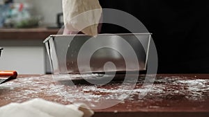 Close-up of hands shaping the dough and placing it into the pan. the cook kneads the dough