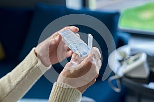 Close-up of hands of sick senior woman holding small plastic pill-box