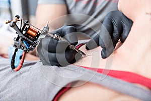Close-up of the hands of a skilled artist making the contour of a tattoo