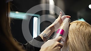 Close Up of Hands of Skillful Hairdresser Straightening Female Hair