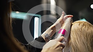 Close Up of Hands of Skillful Hairdresser Straightening Female Hair