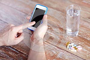 Close up of hands with smartphone, pills and water