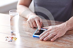 Close up of hands with smartphone, pills and water