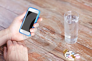 Close up of hands with smartphone, pills and water
