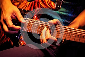 close-up of hands strumming an electric guitar with plectrum
