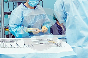 Close up hands of surgery assistant prepearing steralized surgical tools for surgery operation. Selective focus