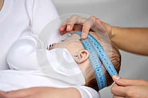 Close up of hands with tape measuring baby head