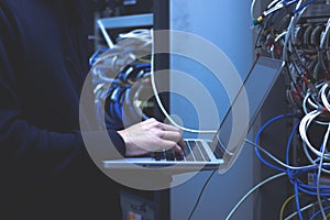 Close up of hands technician working on laptop in data center.