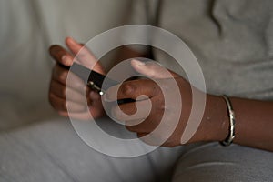 close-up of the hands of a teenager african man boy holding a phone on a gray background game