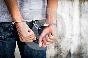 Close up hands tied up handcuffs in behind his body. Arrested man handcuffed hands at the back