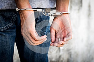 Close up hands tied up handcuffs in behind his body. Arrested man handcuffed hands at the back