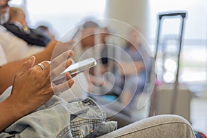 Close up hands of traveller or tourist using smartphone for connecting people in airport shows blurred background of tourist