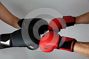 Close-up hands of two boxers in red and black boxing gloves closed for sports greeting on a light background with space for copy